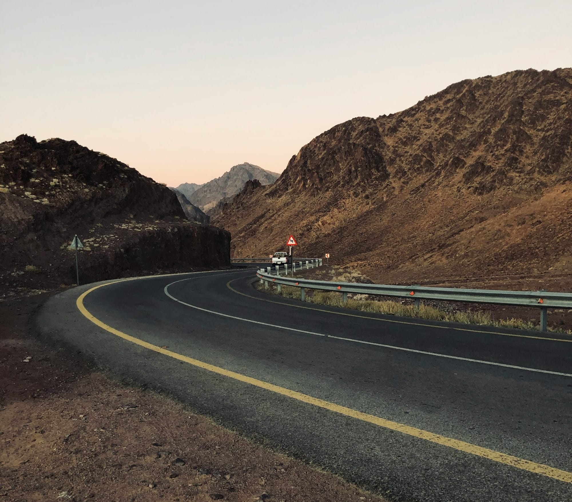 black asphalt road near brown mountain during daytime